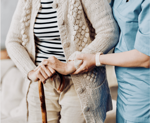 Staff assisting a resident with a cane in a cozy environment