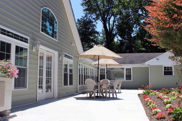 Outdoor patio with seating and umbrellas at Clifton Woods Memory Care Home