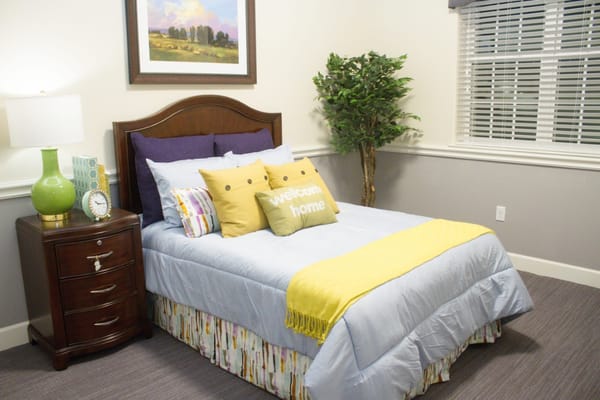 Brightly decorated bedroom with a bed, pillows, and a lamp.