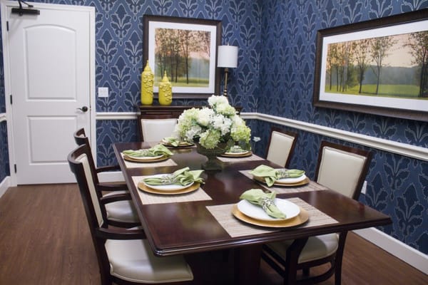 A beautifully set dining table with green napkins and floral centerpiece in a decorated room.
