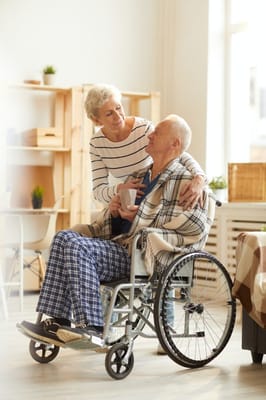 A senior woman interacting with a man in a wheelchair