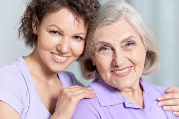 A caregiver and a senior resident smiling together