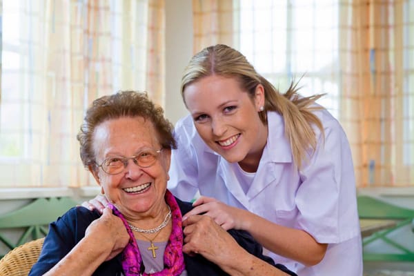 Caregiver smiling with a senior resident in a well-lit room