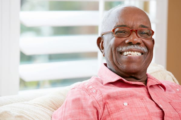 A smiling senior man sitting on a couch