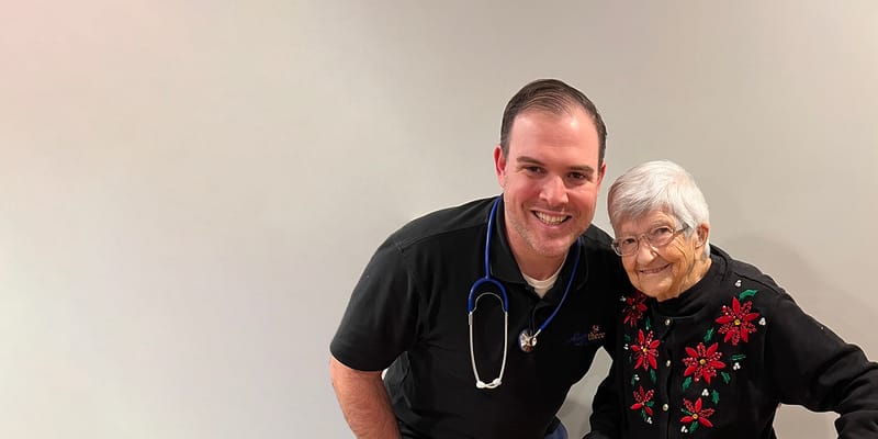 A staff member smiling with a resident in an indoor setting