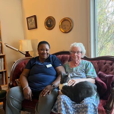 Caregiver sitting with resident and cat on a sofa