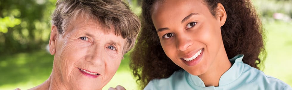 Caregiver and resident smiling outdoors