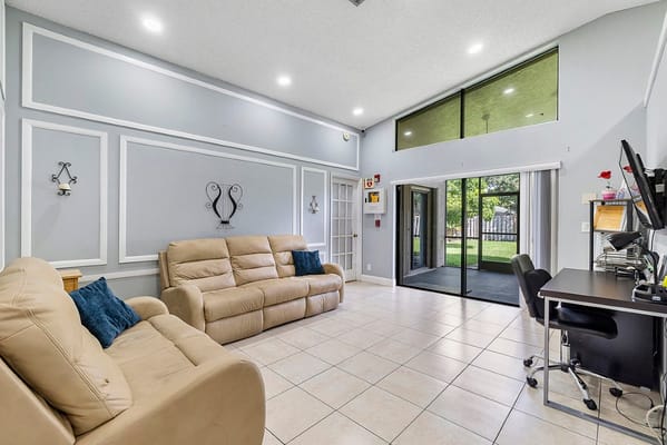 Lounge with beige sofas and a desk in Westbridge Assisted Living Facility.