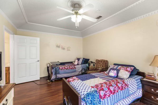 Cozy resident room with two beds and a ceiling fan