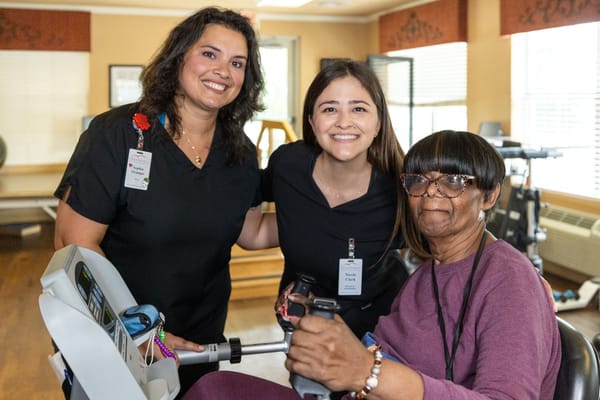 Staff and resident smiling in a rehabilitation room