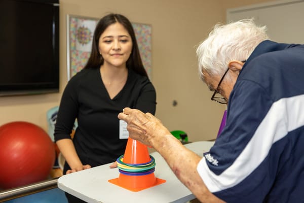 Senior resident engaging in an activity with staff assistance