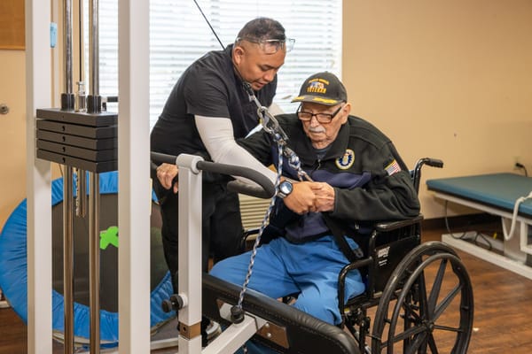 Staff assisting a resident with exercise equipment