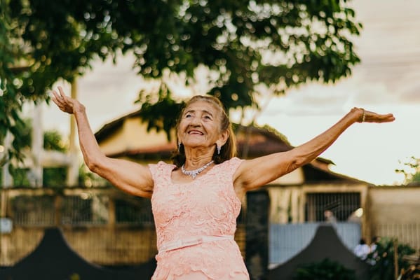 Senior woman joyfully posing outdoors with arms raised