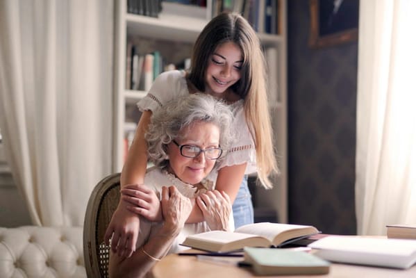 An older woman and a young girl reading together in a cozy room