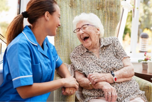 Staff member laughing with a resident in a cozy setting