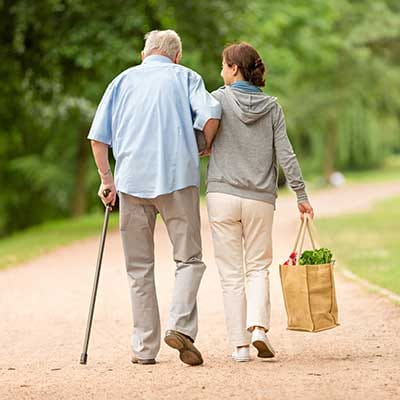 A caregiver assisting a senior on a walking path