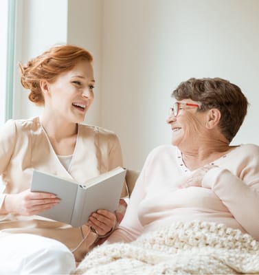 Staff member reading to a resident in a cozy indoor setting