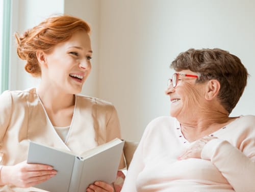 Caregiver reading to a smiling resident