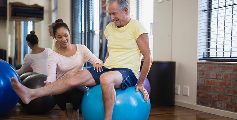 Resident exercising with a therapist in a bright activity room