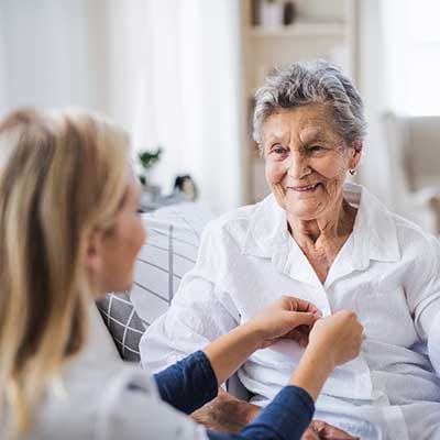 A caregiver assisting a senior woman in a bright room