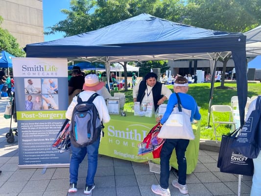 People interacting at a SmithLife Homecare booth during an outreach event