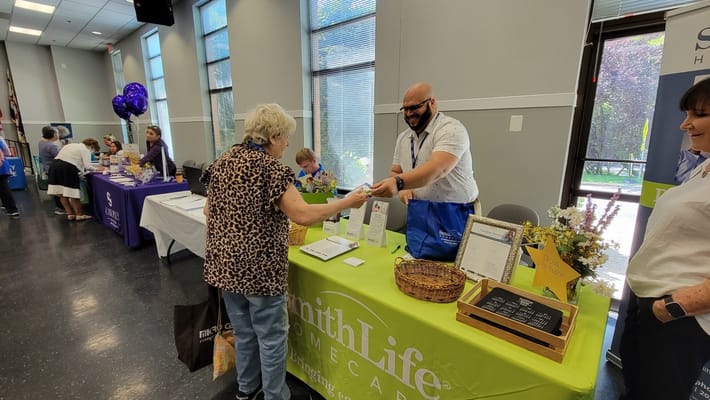 A visitor receiving information from a staff member at the SmithLife Homecare booth.