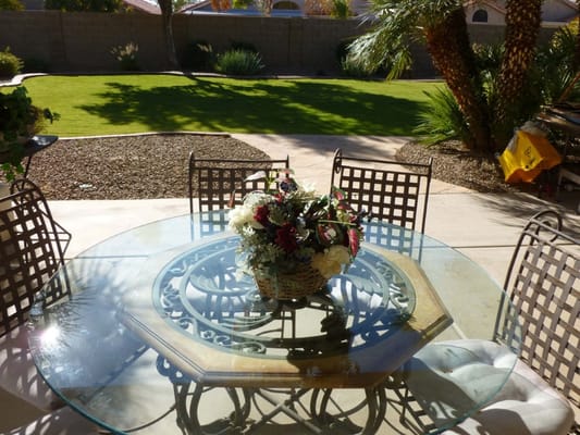 Glass tabletop with floral arrangement on a patio.