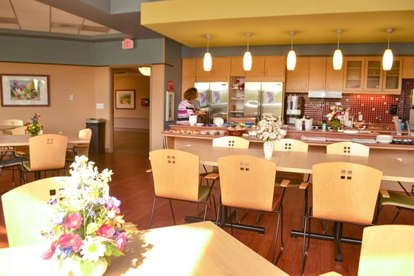 Dining room with residents and food preparation in the background