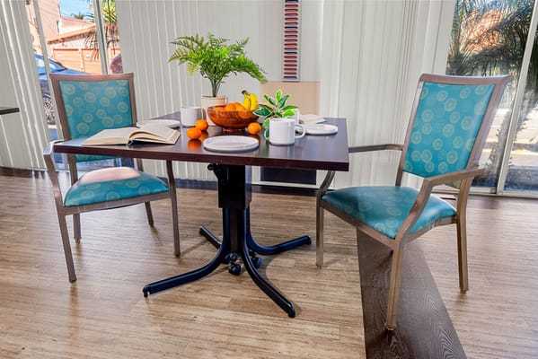 Bright dining area with table, chairs, and fruit
