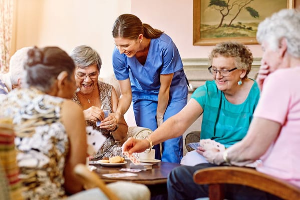Residents and staff engaged in a card game in a common area