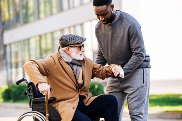 Caregiver assisting a resident in a wheelchair outdoors