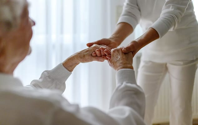 Caregiver holding hands with a senior resident