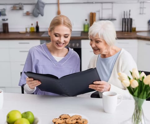 A caregiver and resident smiling over a photo album