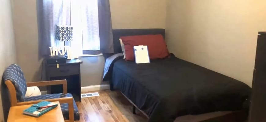 A bedroom featuring a bed, nightstand, and a chair.