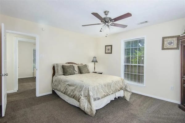 A spacious bedroom with a queen-sized bed and a window.