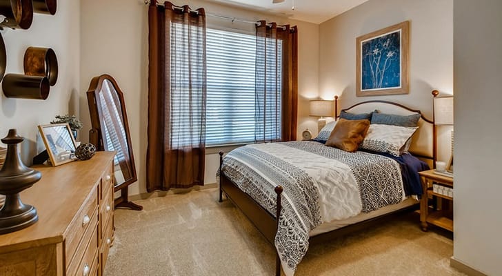 A well-decorated bedroom featuring a bed, dresser, and a mirror.