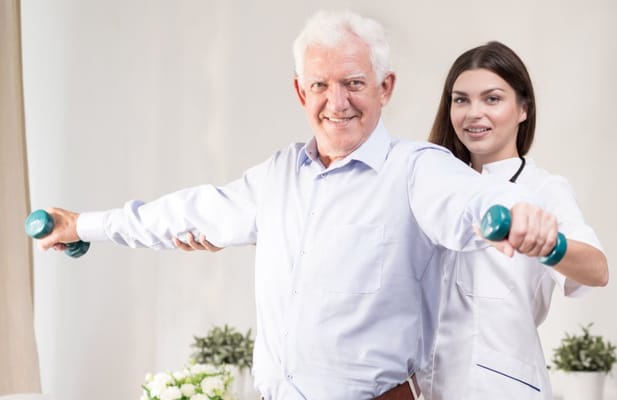 Resident exercising with a caregiver using dumbbells