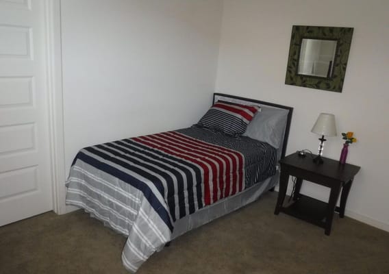 Simple bedroom setup with striped bedding and lamp