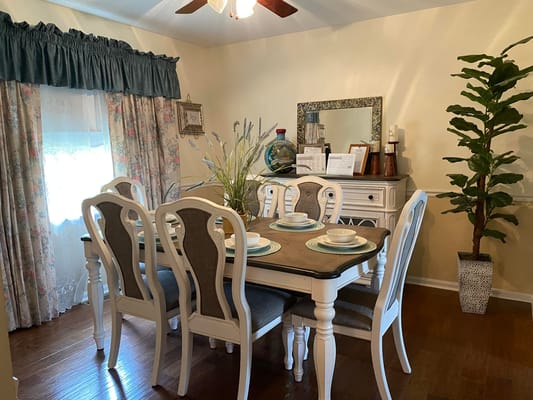 Dining room with table and chairs, decorative curtains, and a plant