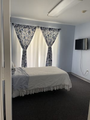 Private bedroom with a bed and floral curtains in Arden Valley Homecare