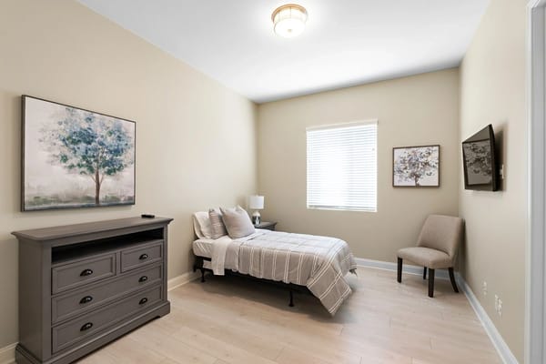 Well-lit private room with a bed and artwork