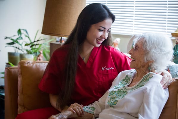 Caregiver and resident smiling together in a cozy living room