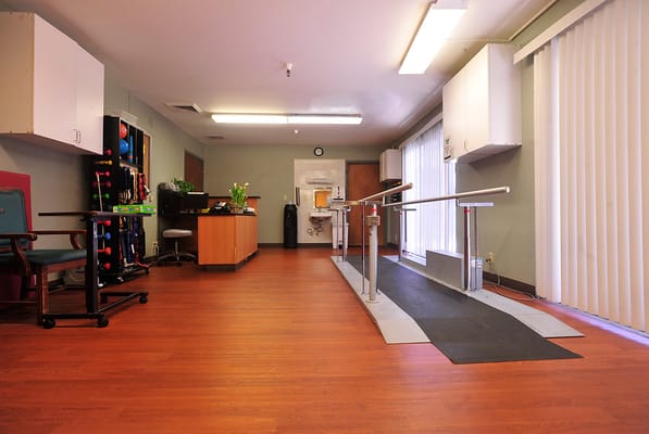 Rehabilitation room with therapy equipment and wooden floors