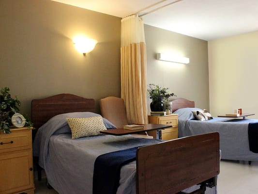 A shared resident room with two beds and bedside tables