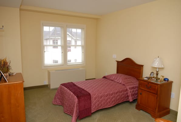 A private resident room with a bed and nightstand