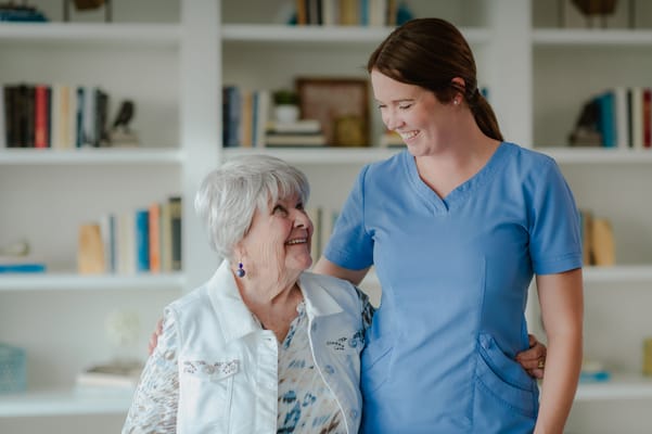 Caregiver smiling with a resident in a bright common area