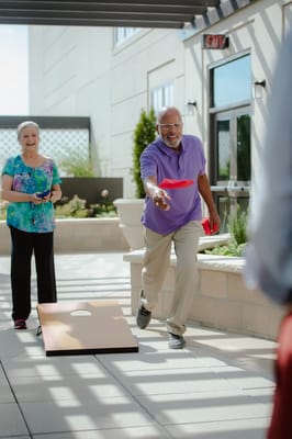 Residents playing cornhole in an outdoor area