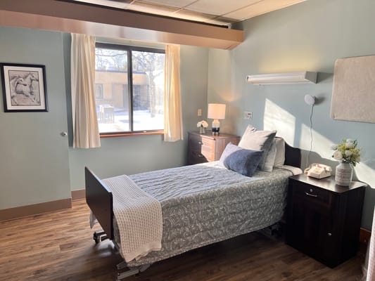 A cozy bedroom with a single bed, bedside table, and window.