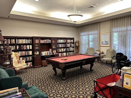 A cozy common area with a pool table and bookshelves