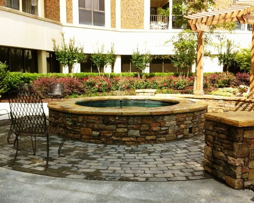 Outdoor seating area with a stone fountain and garden